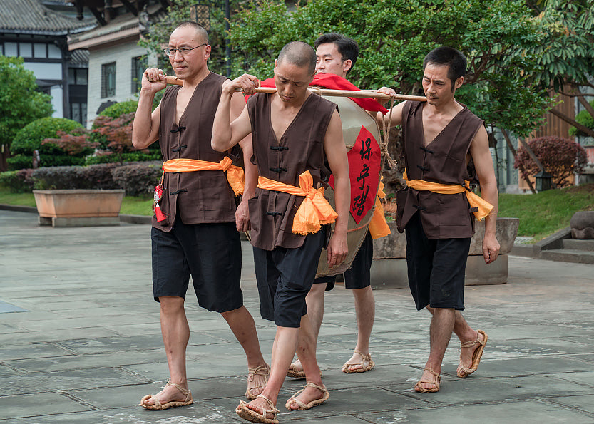 Vinegar in a large crock being carried by four men