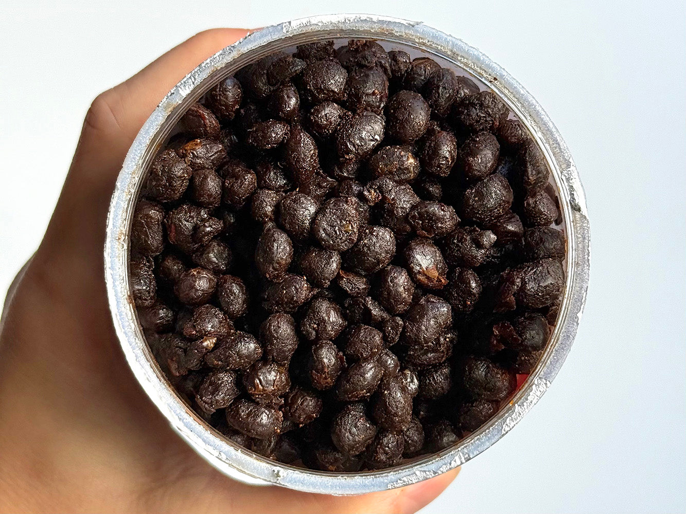 an overhead view of a jar of fermented black beans with the lid off, showing the individual fermented soybeans