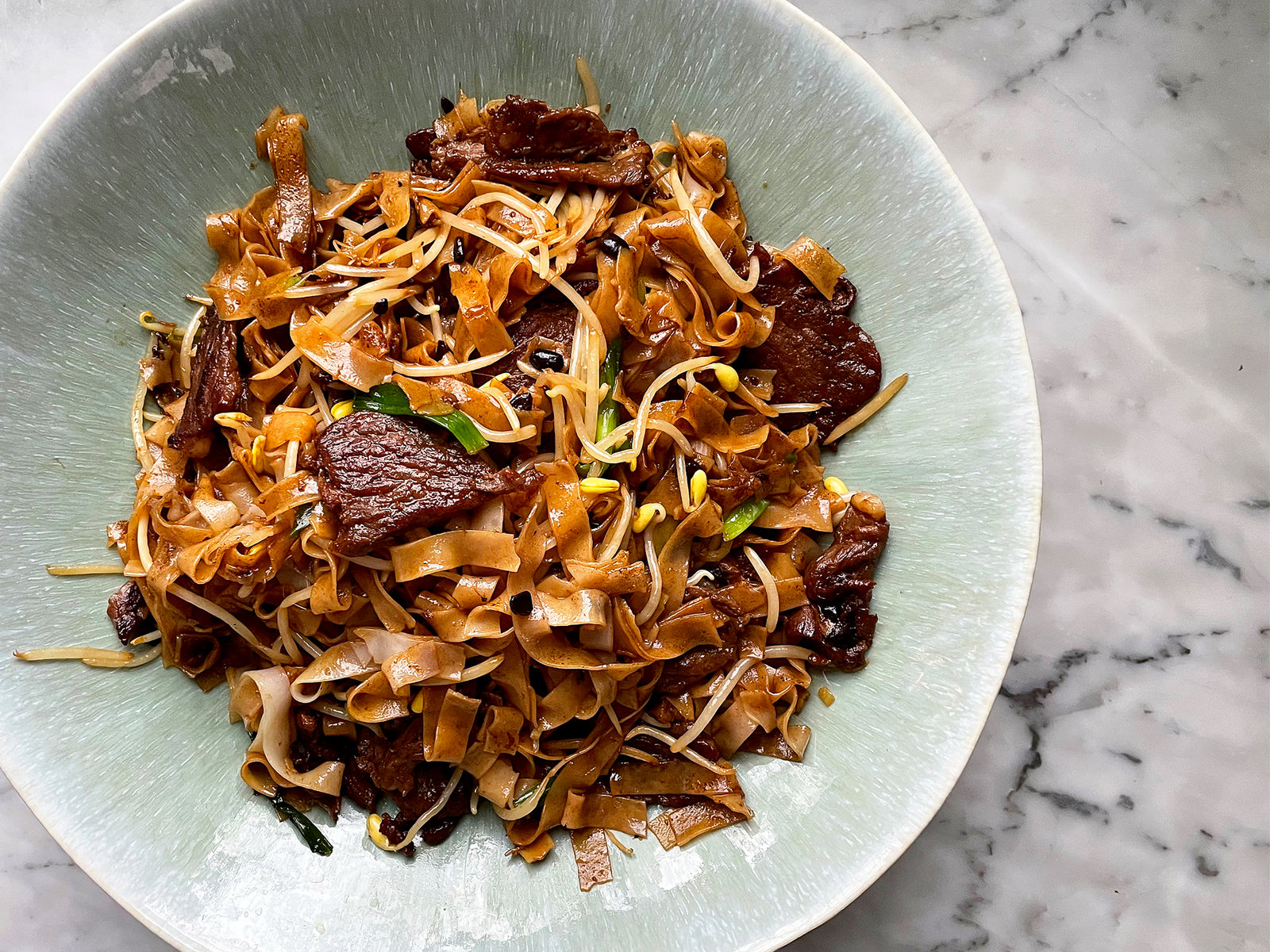 Beef chow fun in a green bowl