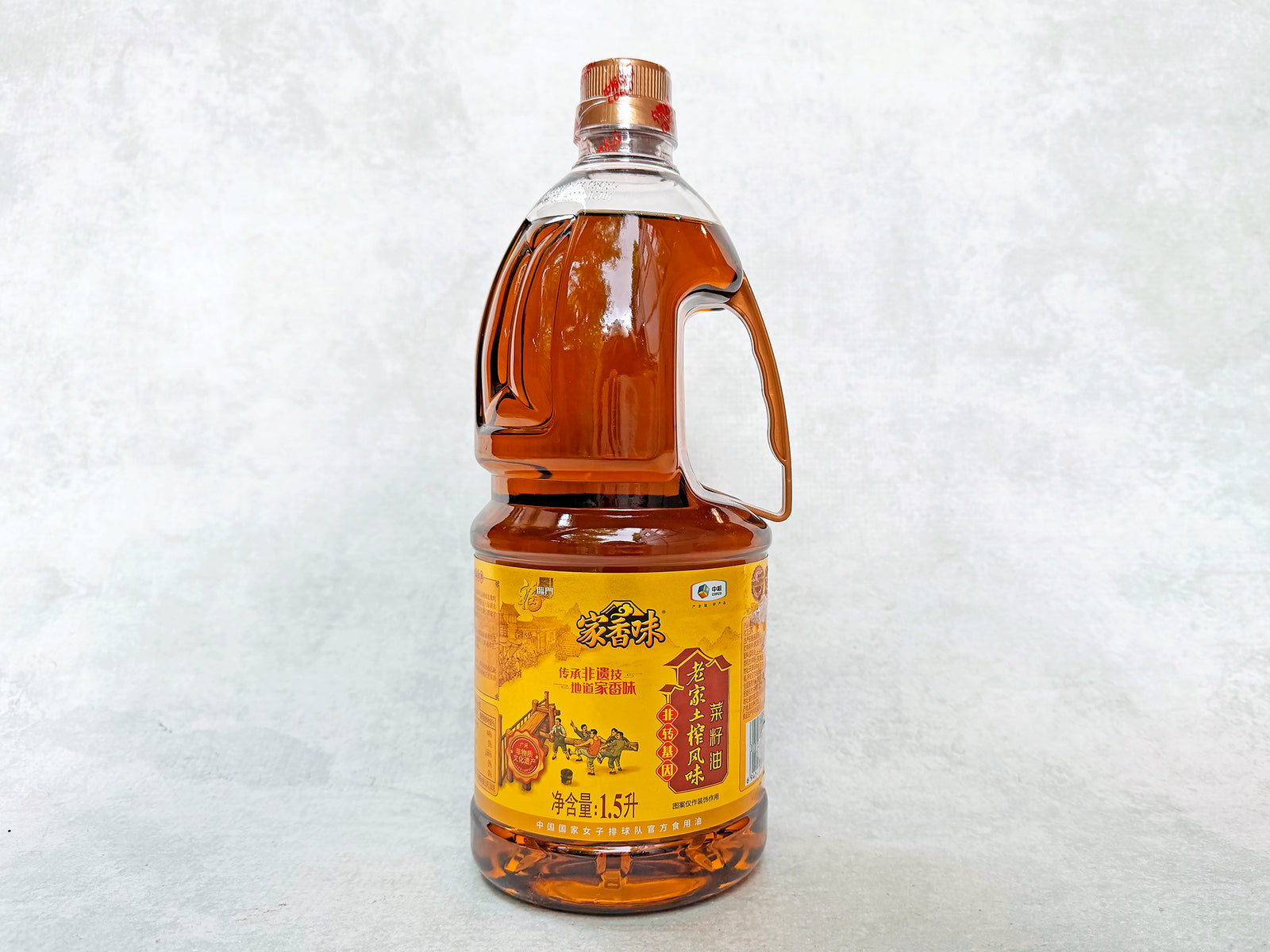 Sichuan roasted rapeseed oil in a 1.5 liter bottle. The oil is golden and the label shows drawings of traditional production methods. 