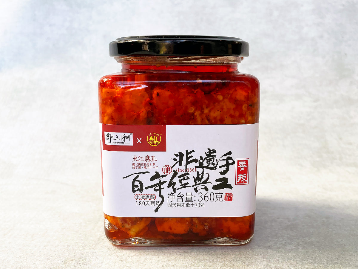 a square glass jar with cubes of tofu in a bright red oil, with a label that has Chinese characters