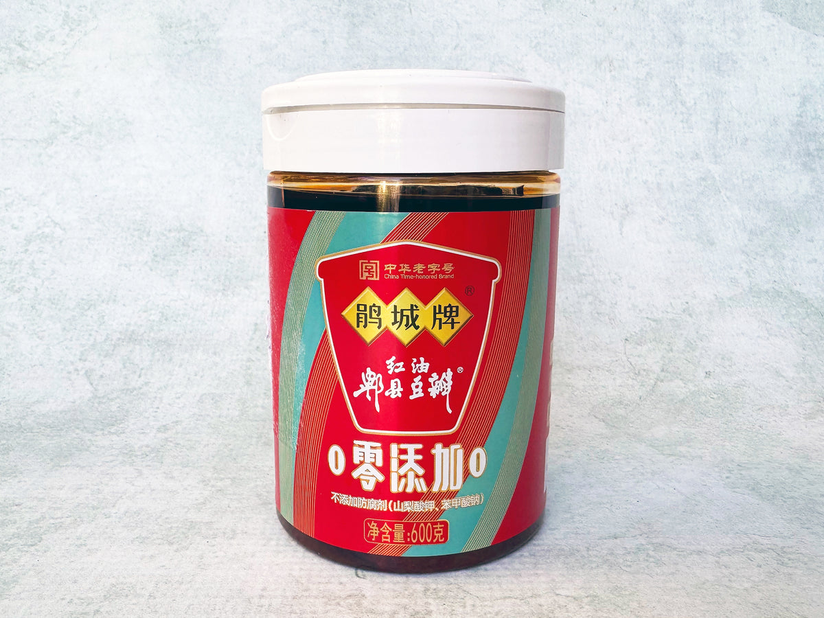 a resealable plastic jar of red-oil Pixian doubanjiang with a red and blue label