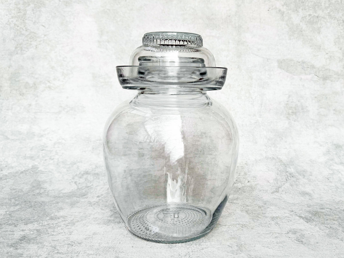 a clear glass pickle jar with a glass water moat and a glass cap