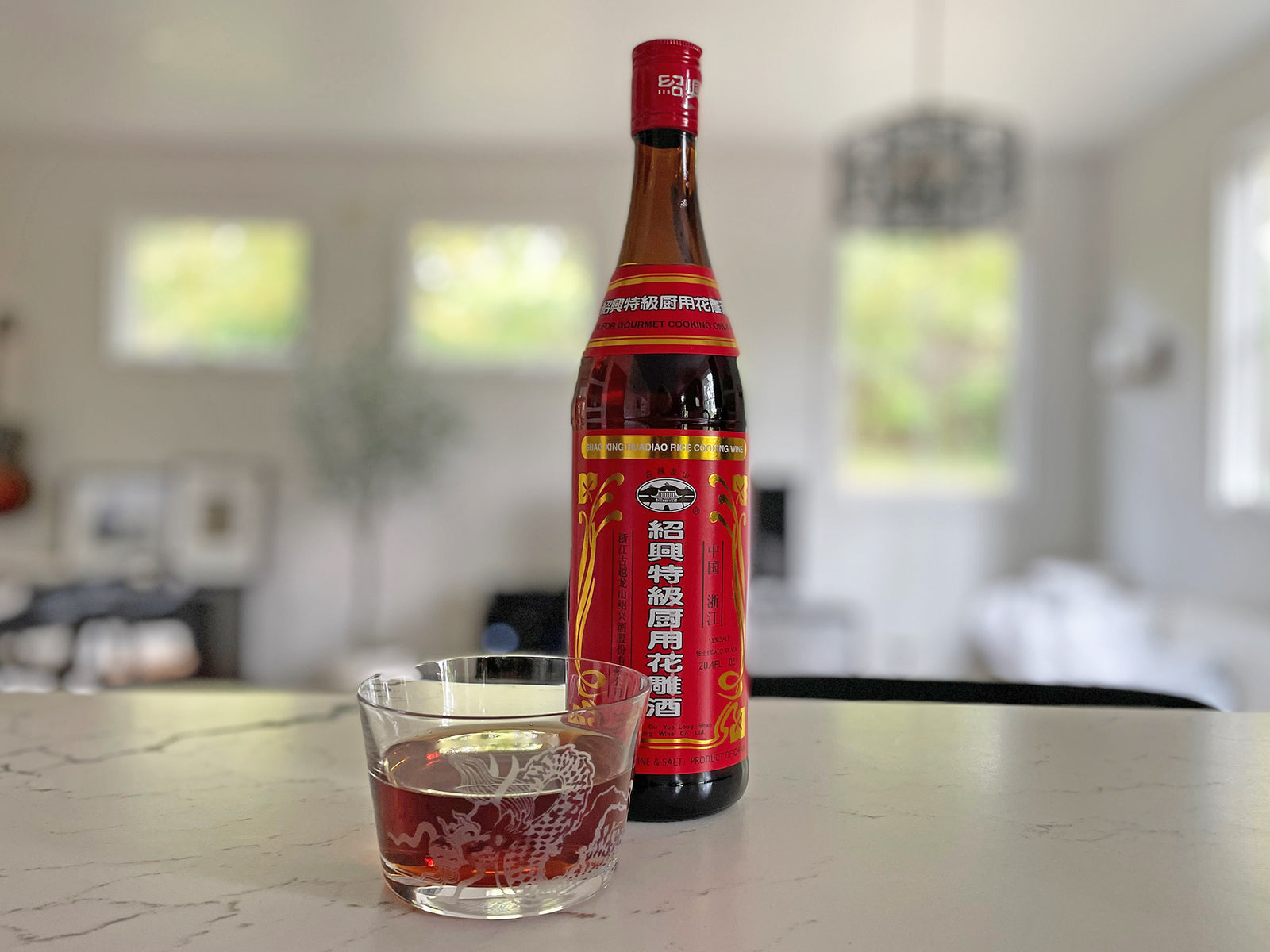 A bottle of Shaoxing wine and a cup holding the amber colored wine