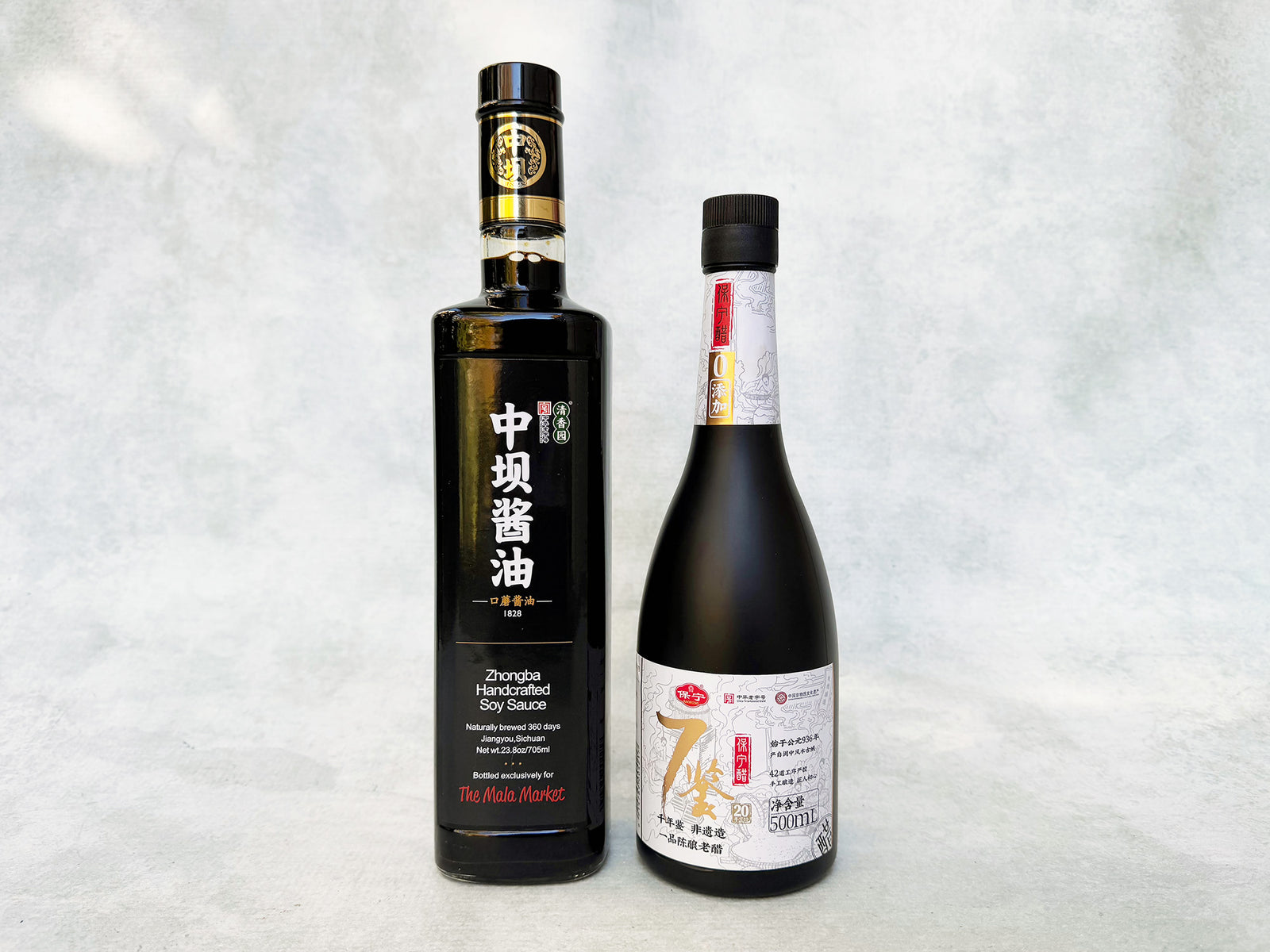 a tall bottle of premium Sichuan soy sauce and a bottle of 20 year Sichuan vinegar with classic black, white and gold labels