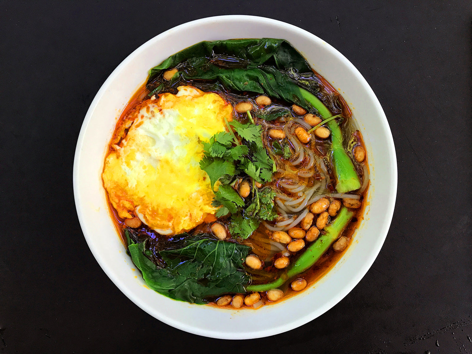 A bowl of sweet potato glass noodles in spicy broth with egg