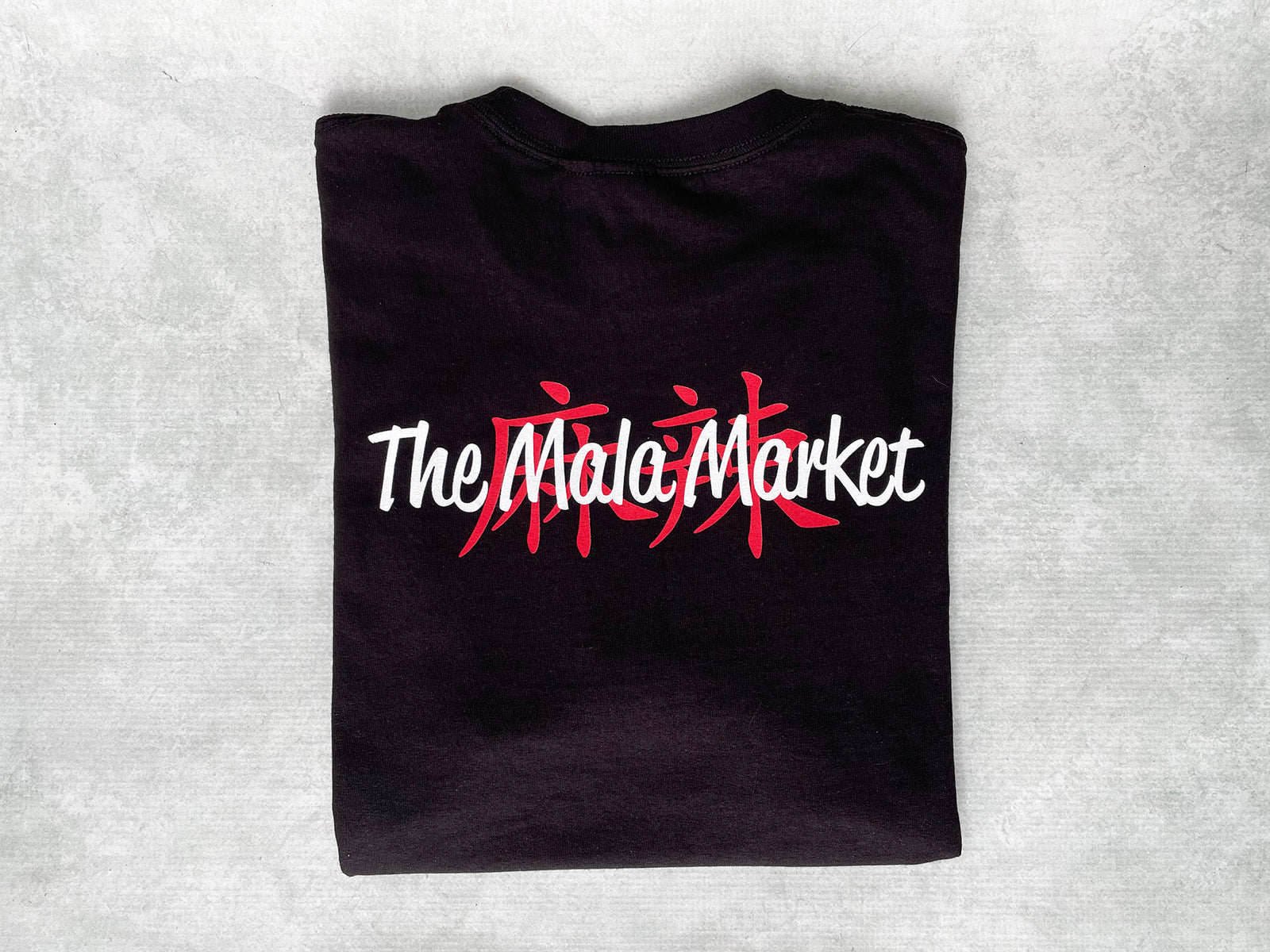 a black folded t-shirt with the Mala Market logo on the back