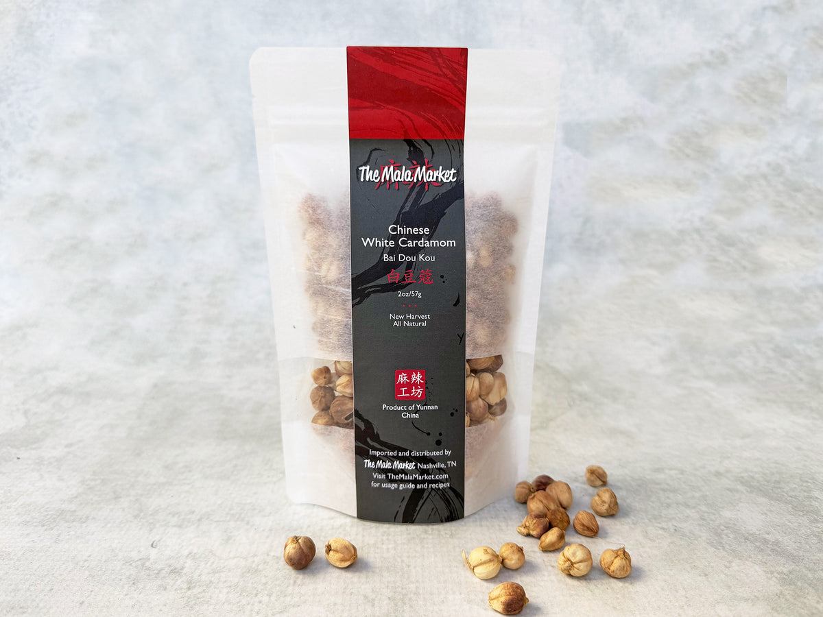 round white cardamom pods are scattered in front of a white kraft bag