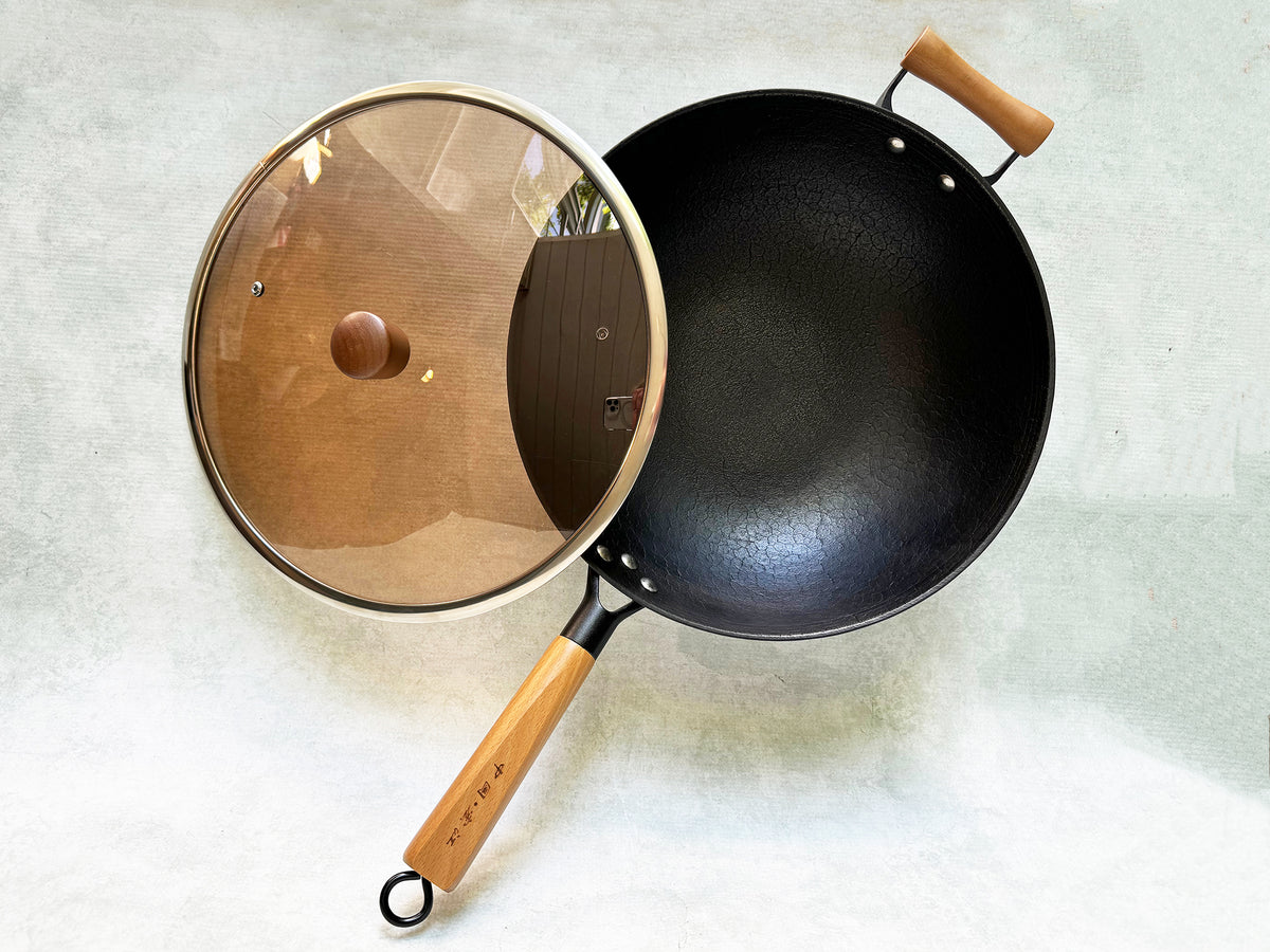 Overhead view of cast-iron wok showing smoked-glass lid with wood knob