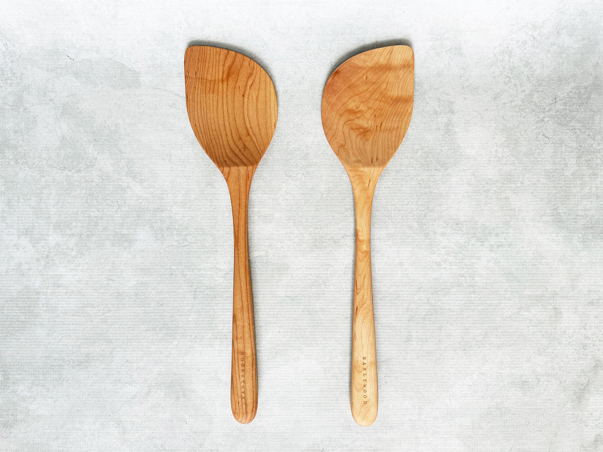 two wooden wok spatulas, one right-handed and one left-handed