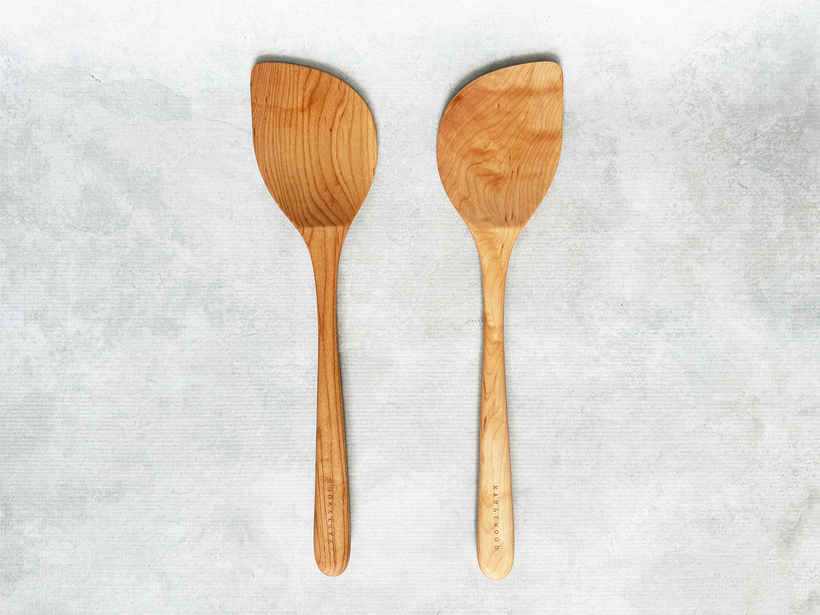 two wooden wok spatulas, one right-handed and one left-handed