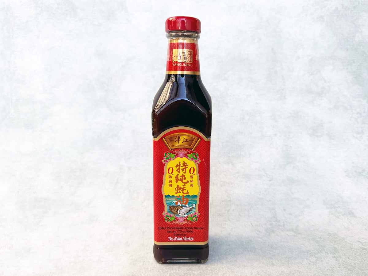 a square glass bottle of extra pure oyster sauce with a red label 