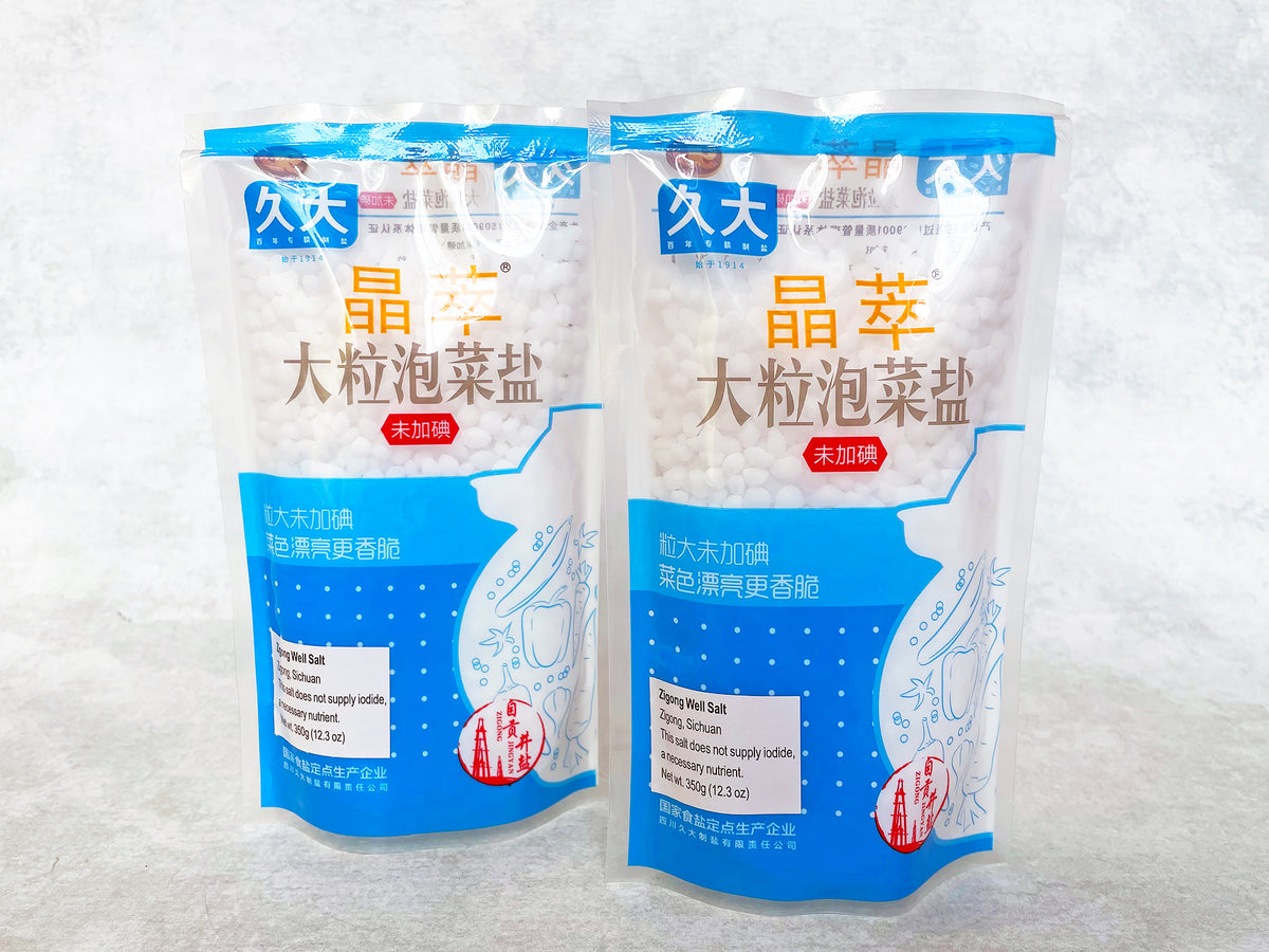 two plastic bags of Zigong well salt for pickling, with the large round pellets of salt visible through the bag