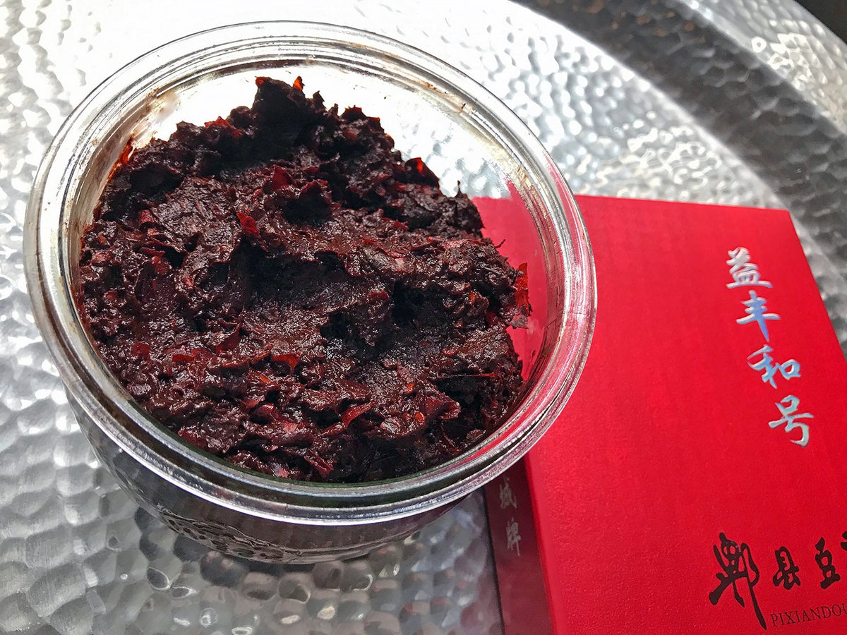 Pixian doubanjiang in a glass jar with its red box packaging beside it