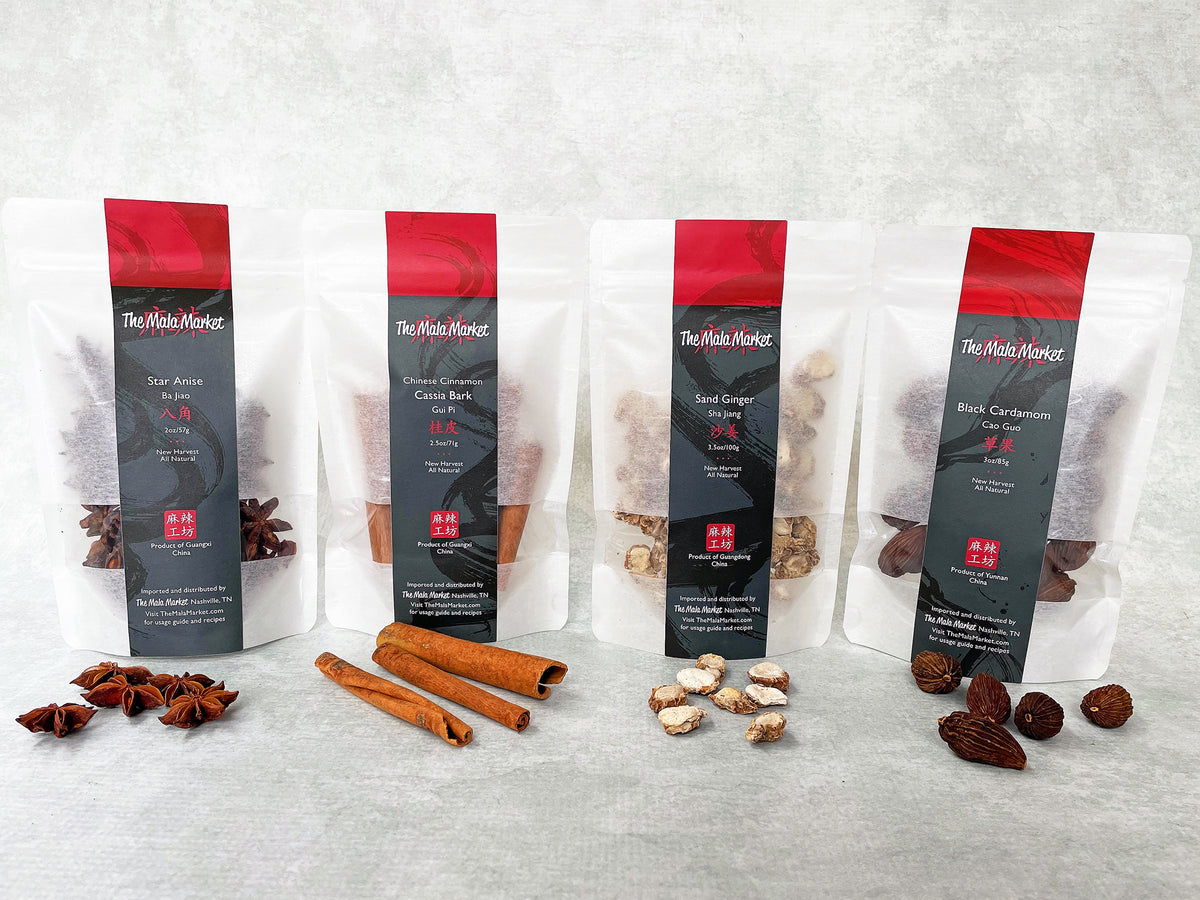 a collection of four spices, each shown in a white kraft bag and with the whole spice also displayed in front of its bag