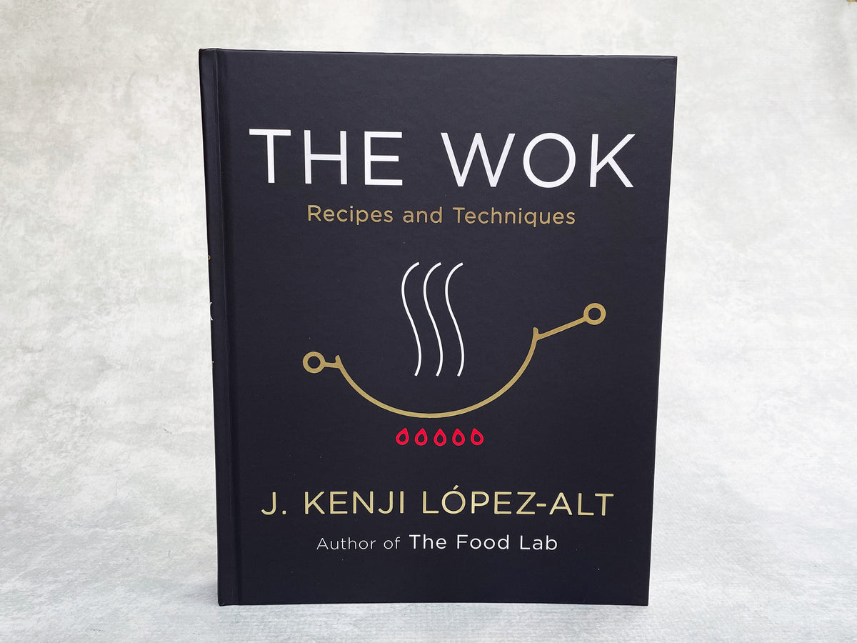 a hardcover copy of The Wok cookbook by J Kenji Lopez-Alt