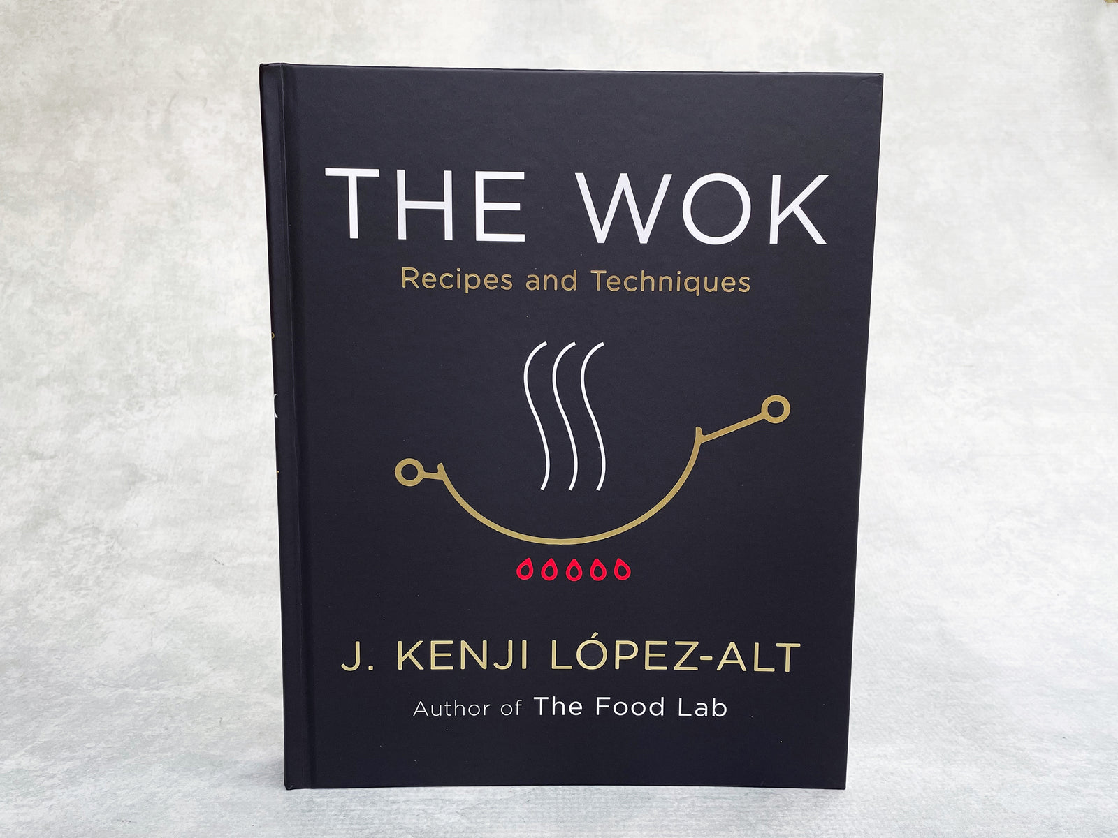 a hardcover copy of The Wok cookbook by J Kenji Lopez-Alt
