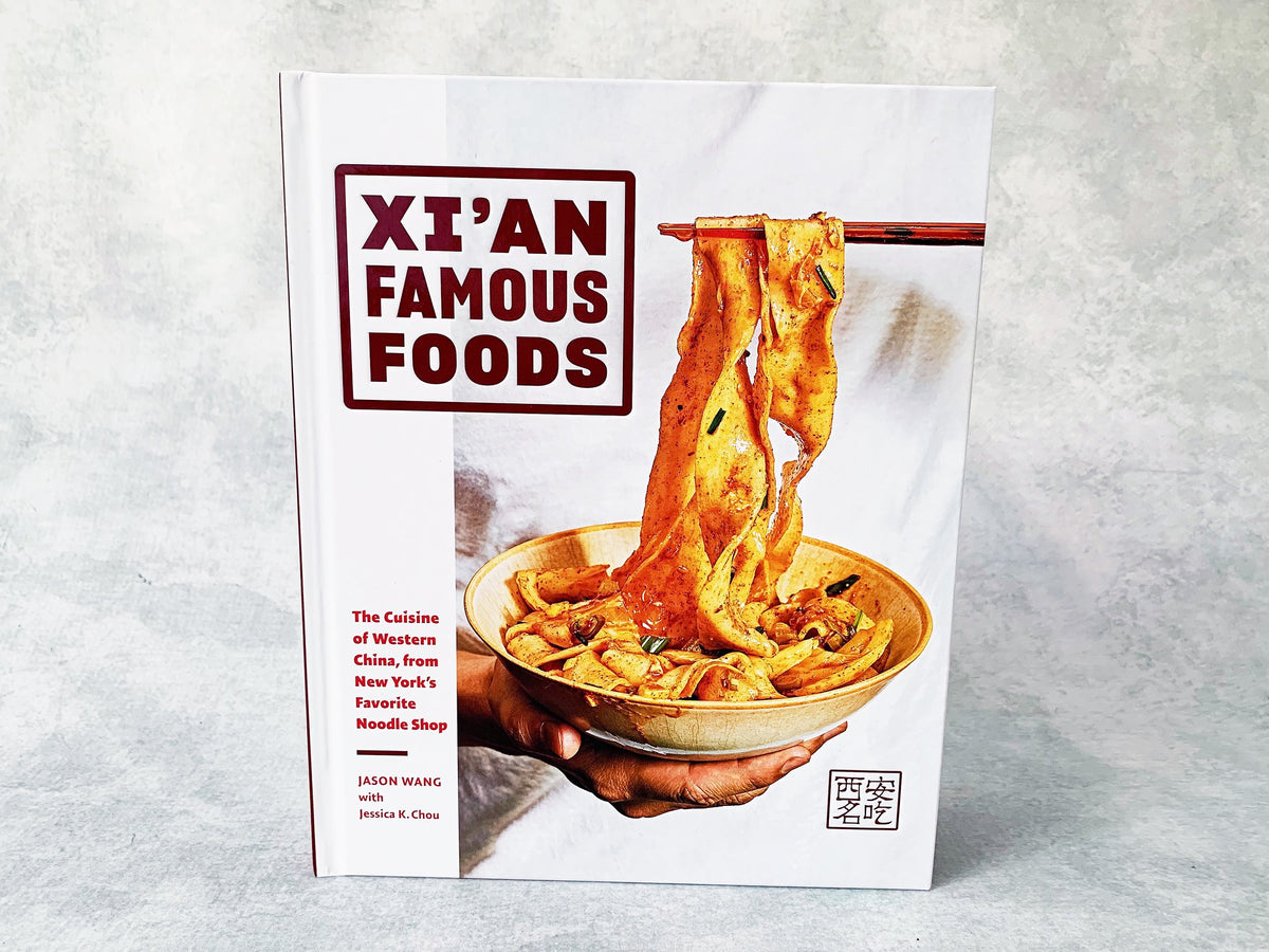 a hardback copy of Xi'an Famous Foods cookbook by Jason Wang that shows a bowl of wide noodles on the front