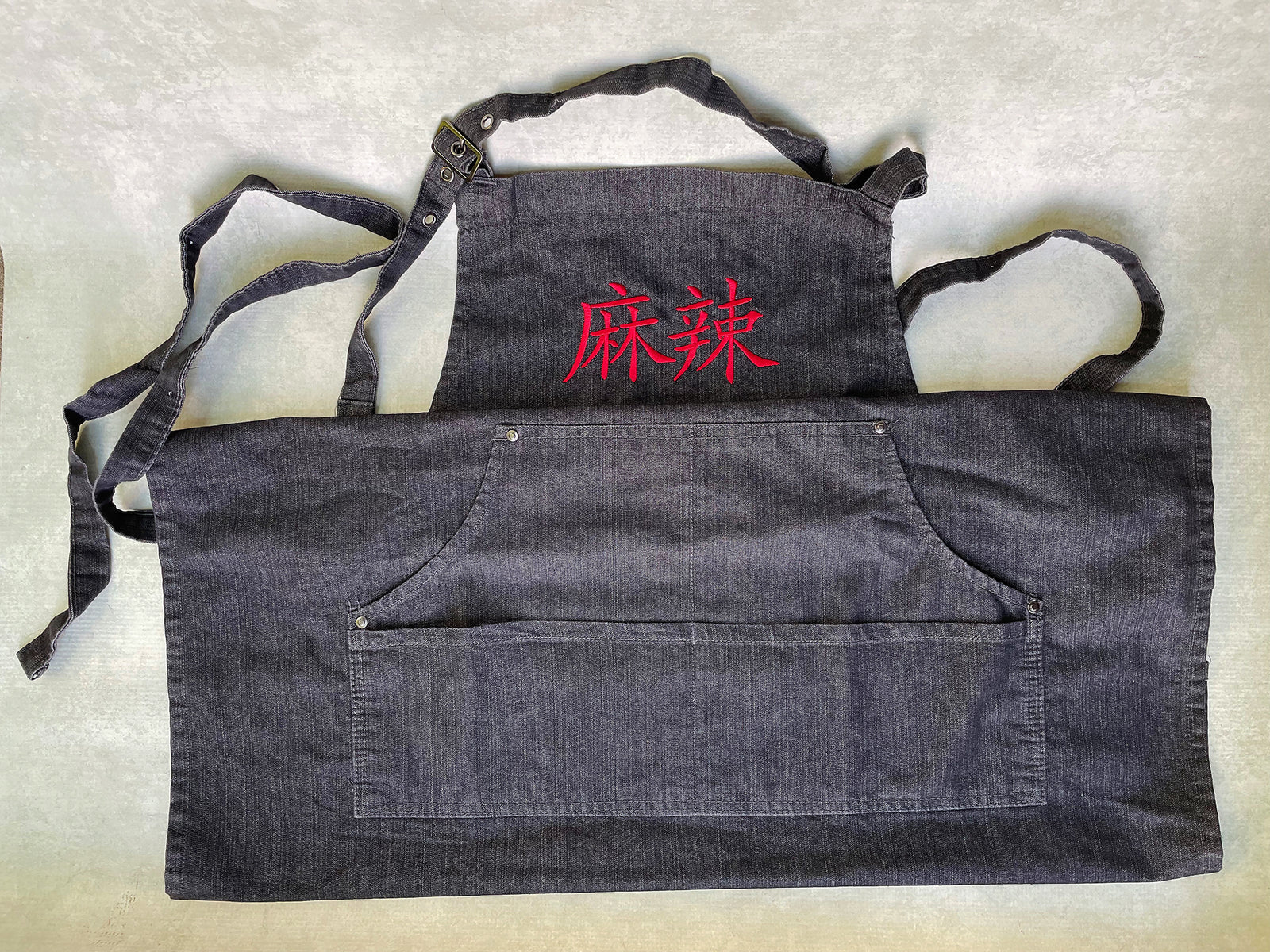 a dark gray cotton apron folded to show the bottom section with two wide pockets