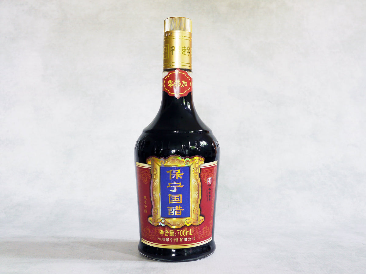 a large glass bottle of Baoning vinegar with a red label and Chinese characters
