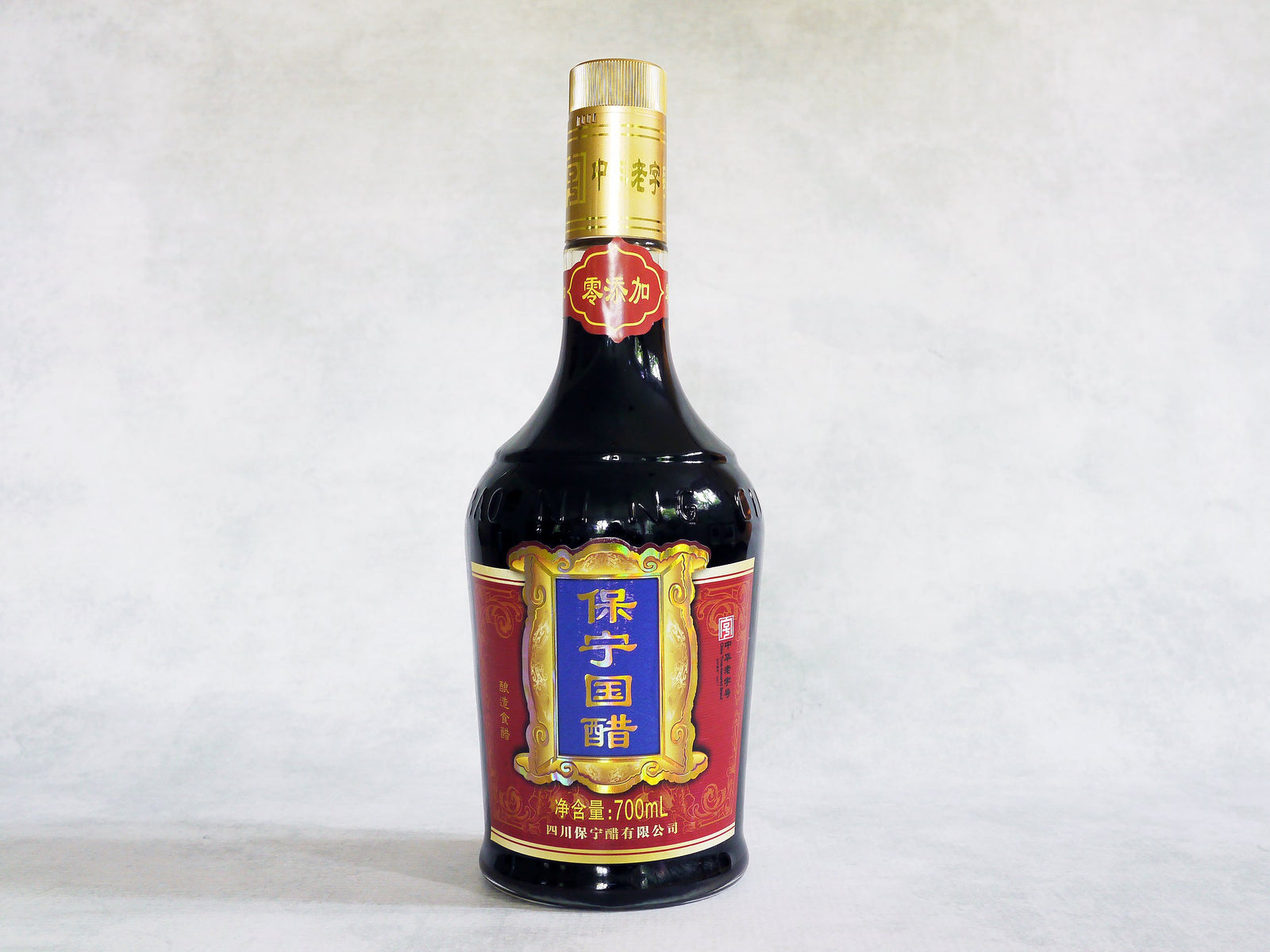 a large glass bottle of Baoning vinegar with a red label and Chinese characters