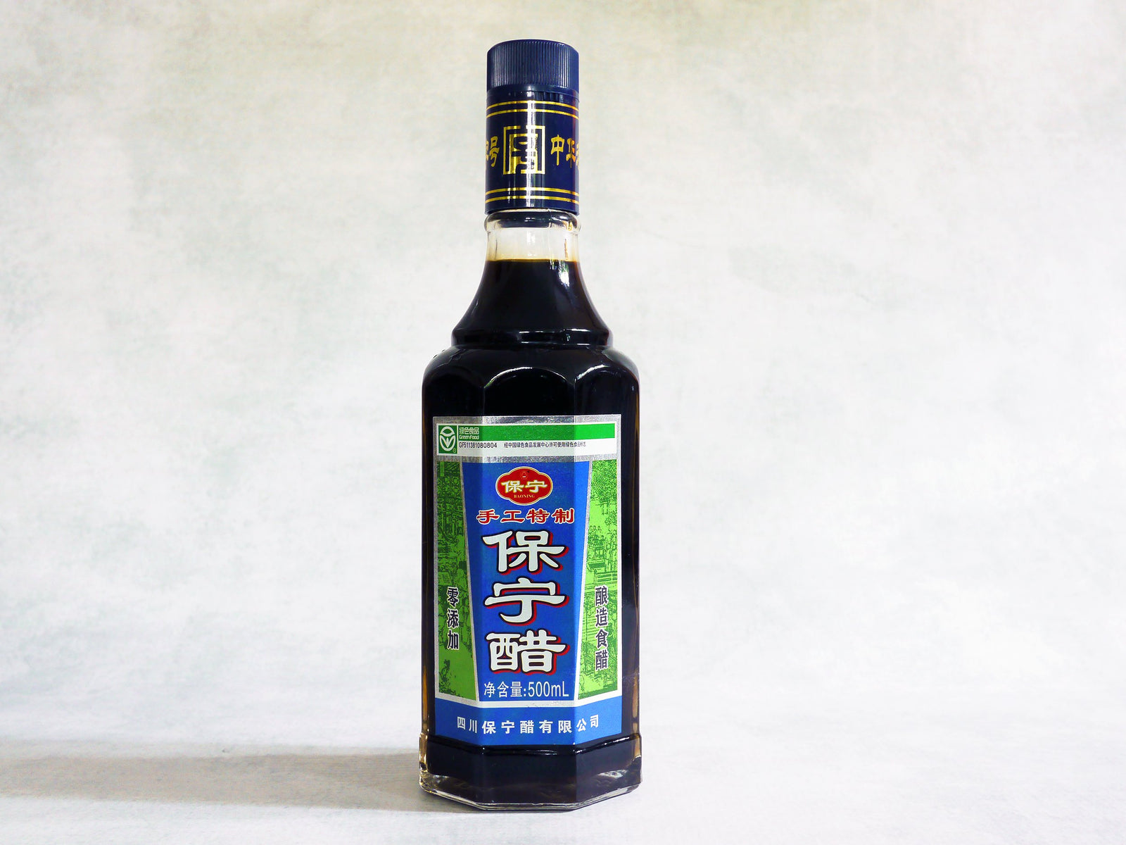 a glass bottle of Baoning vinegar with a blue and green label and Chinese characters