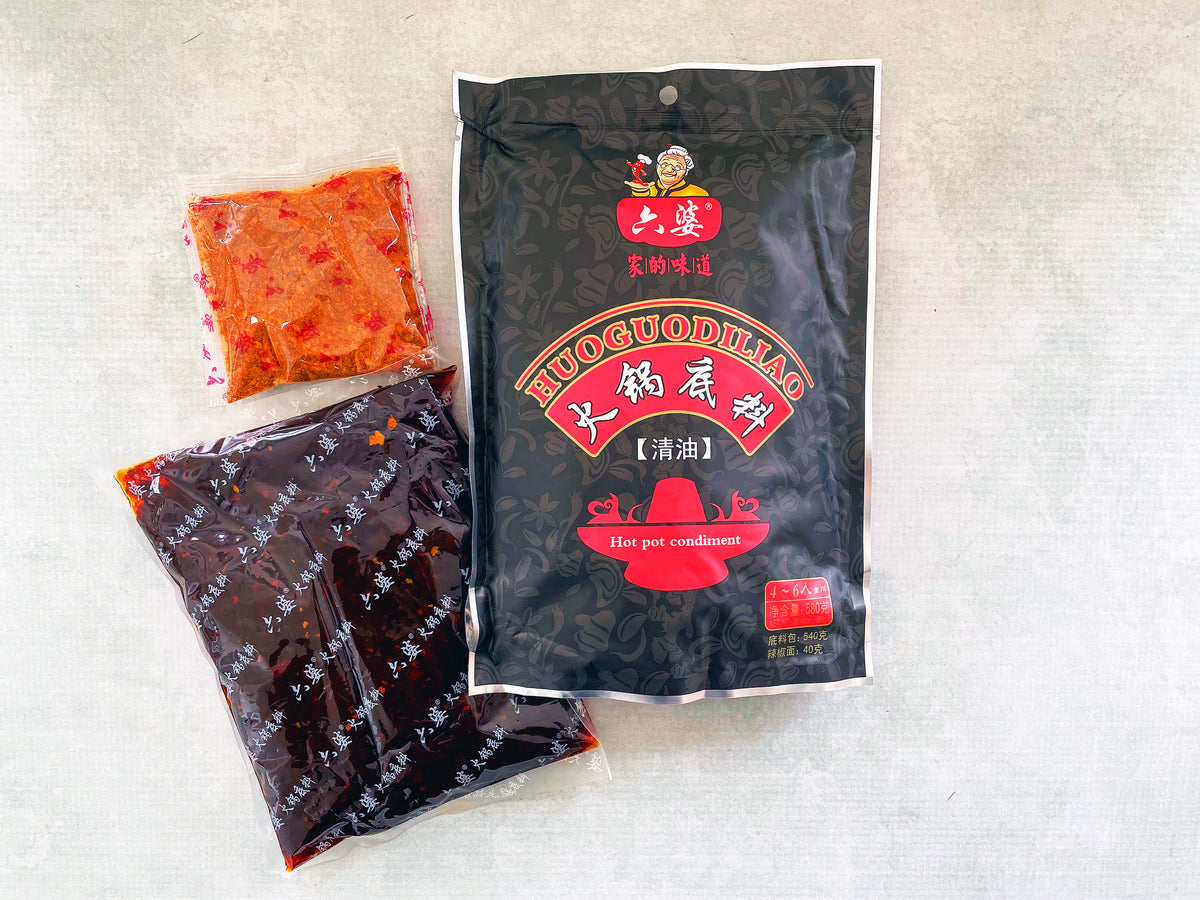 a plastic bag of hot pot  soup base with its contents shown beside it, including one bag of a dark liquid and one bag of a chili powder