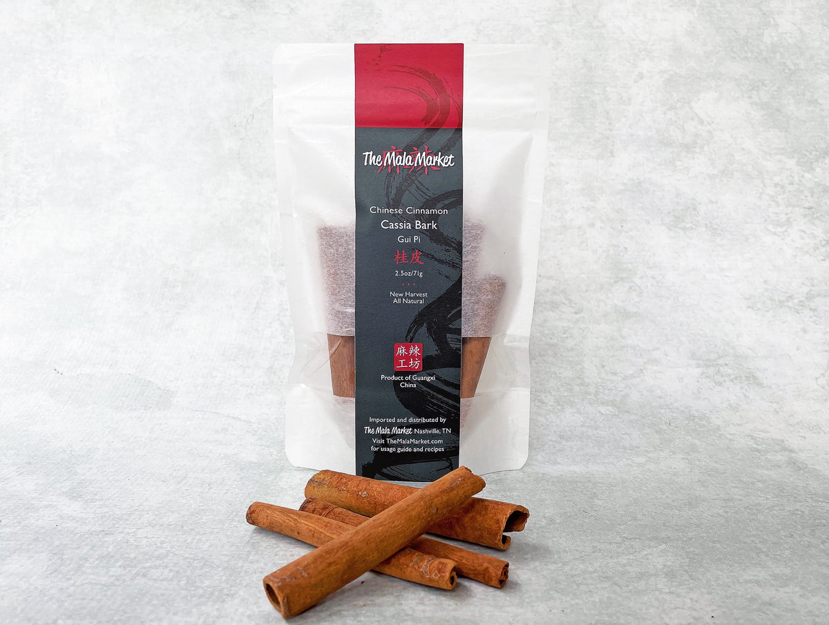 a white kraft bag of cassia bark and a few small rolls of cassia bark in front of it