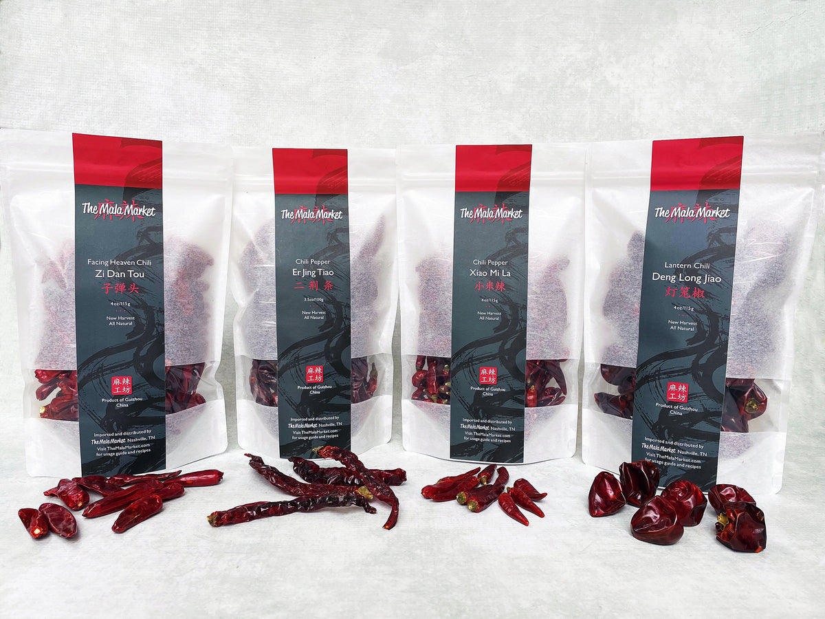 four white kraft bags of dried red chilies, with each different kind displayed in front of its bag, including small, medium, long and round shapes