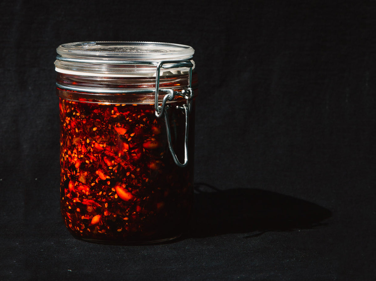 a glass jar of red chili crisp with a metal latch top