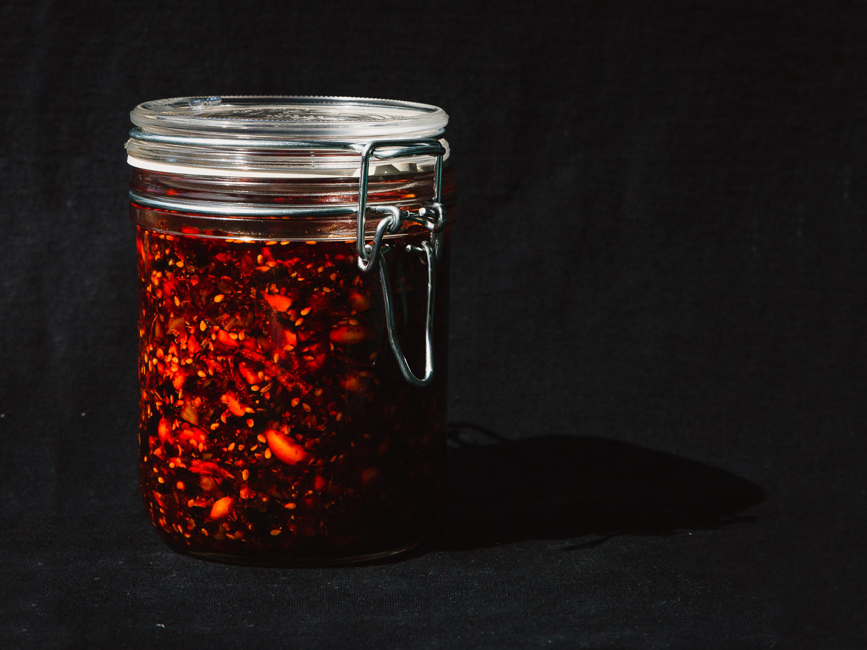 a glass jar of red chili crisp with a metal latch top