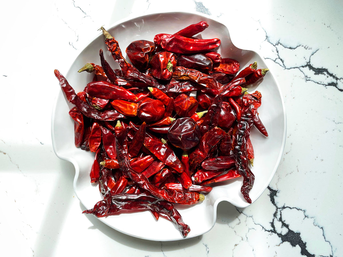 a large white bowl holding a mix of different dried Sichuan chilies