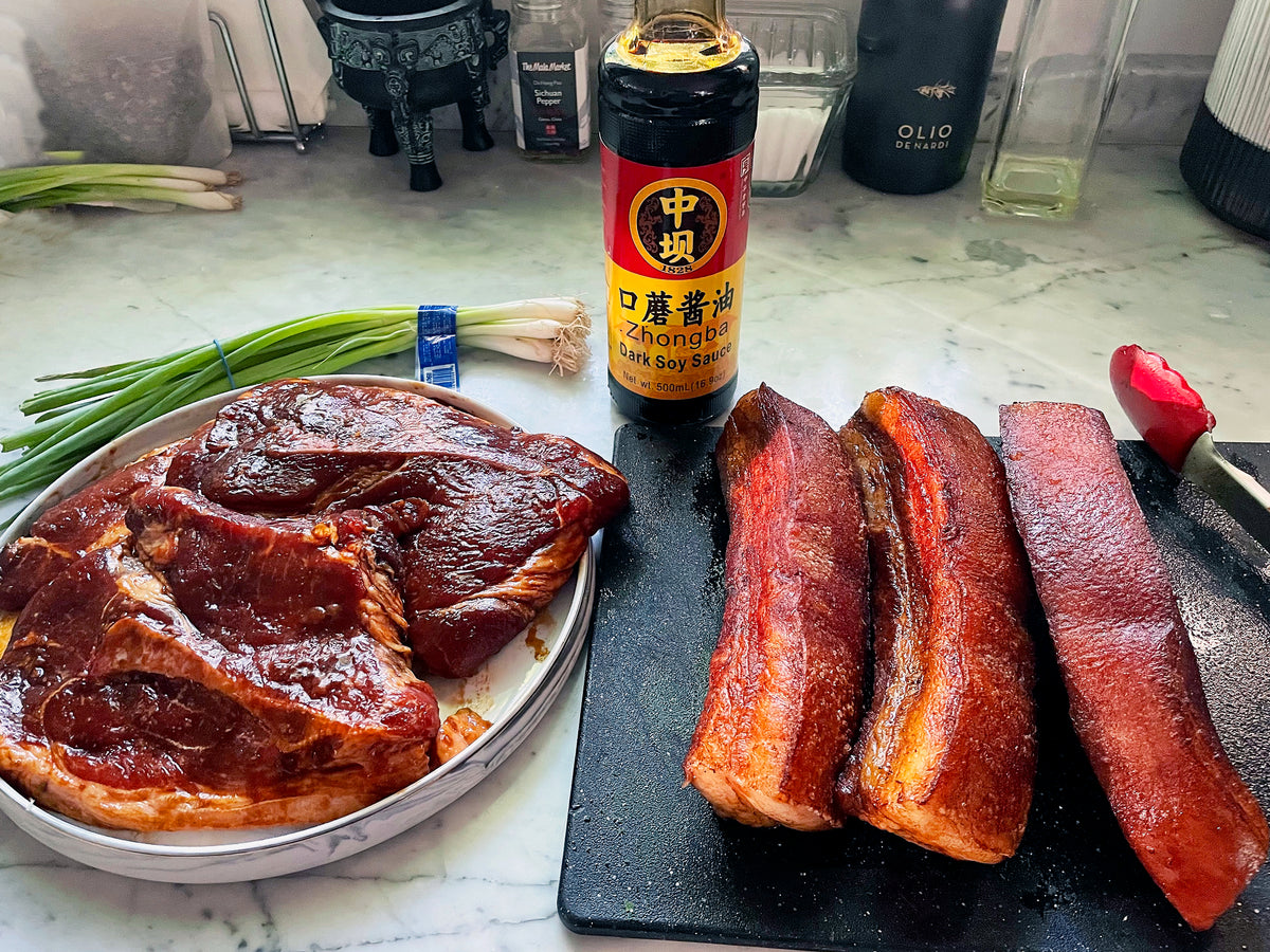 pork belly strips and pork shoulder steaks being marinated in dark soy sauce 