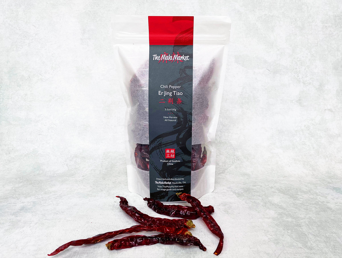 a tall white kraft bag of er jing tiao chilies with long, red, wrinkly er jing tiao displayed in front of the bag