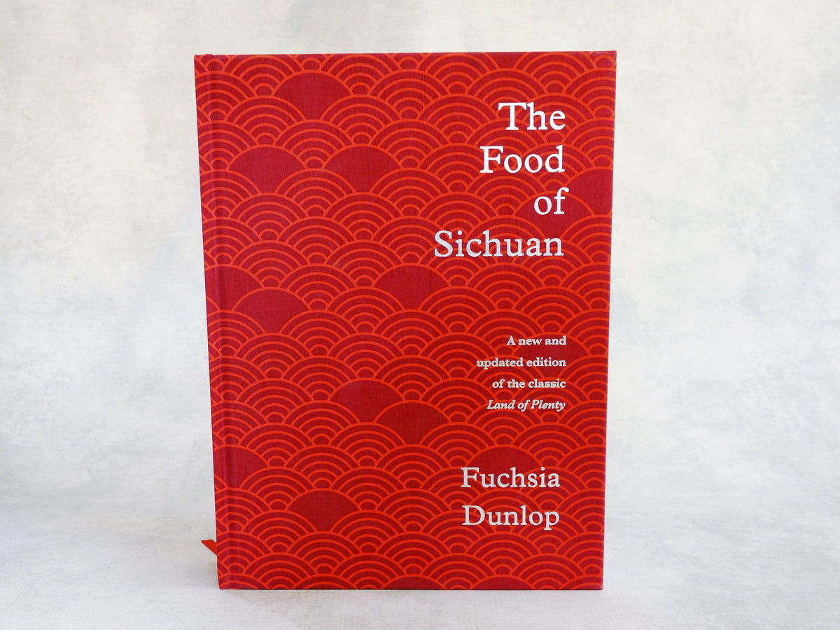 A hardcover copy of the cookbook The Food of Sichuan by Fuchsia Dunlop, a new and updated edition with a red cloth cover