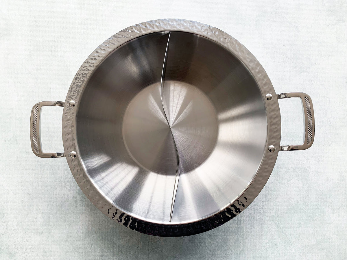 a stainless steel hot pot divided down the center into two compartments, with two side handles