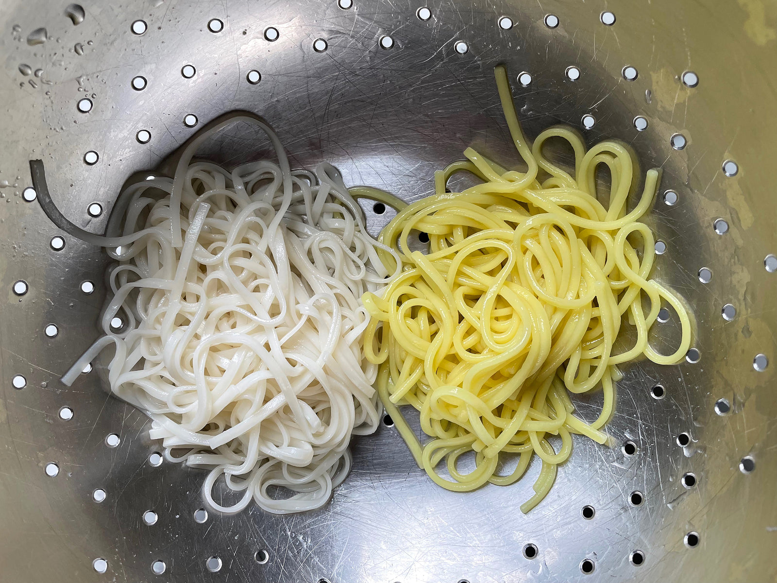 two piles of cooked noodles: a flat, white non-alkaline noodle vs a round, yellow alkaline noodle
