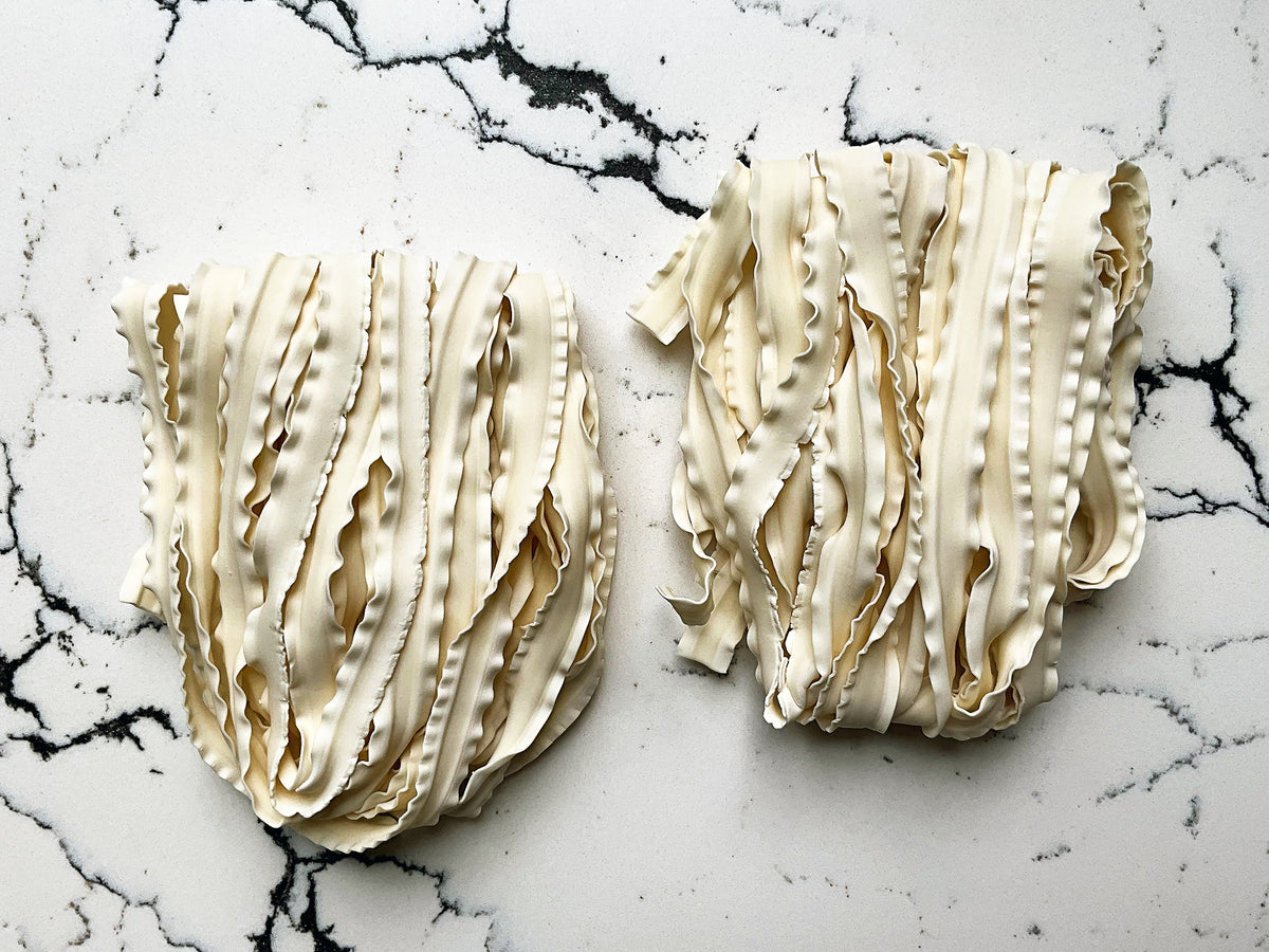 two bundles of wide wavy knife-cut noodles 
