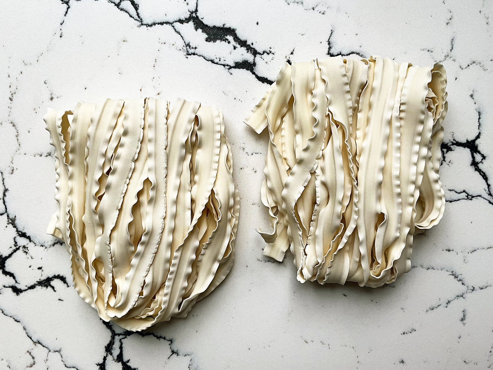 two bundles of wide wavy knife-cut noodles 