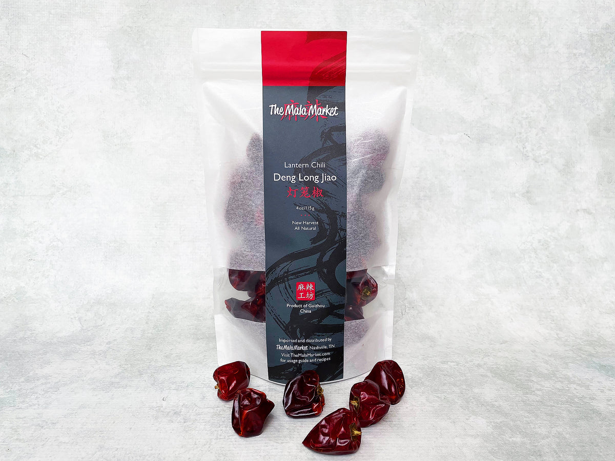 a tall white kraft bag of chilies with some round, deep-red lantern chilies displayed in front of it