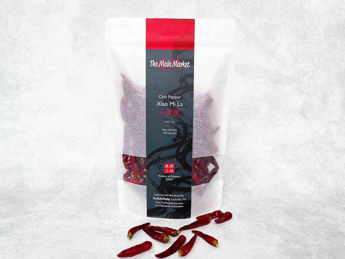 small dried red xiao mi la chilies are shown in front of a large white kraft bag